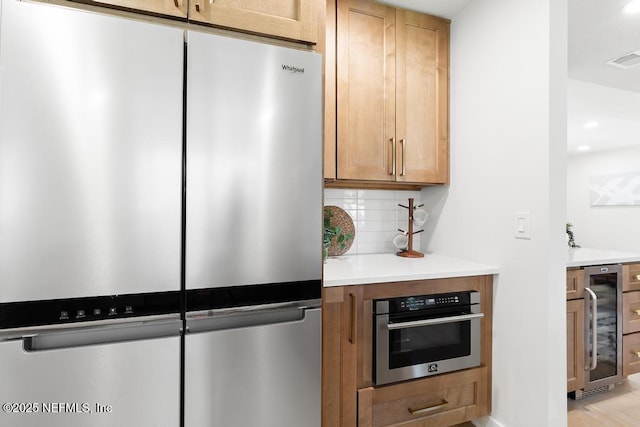 kitchen with visible vents, decorative backsplash, wine cooler, appliances with stainless steel finishes, and light countertops