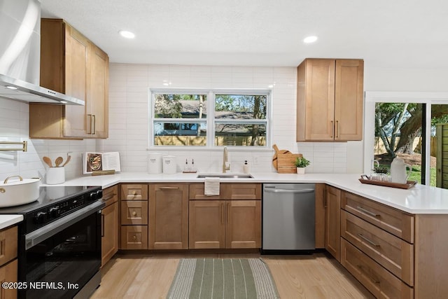 kitchen with stainless steel dishwasher, electric range oven, a sink, wall chimney range hood, and a peninsula