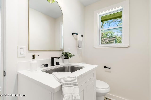 bathroom featuring toilet, vanity, and baseboards