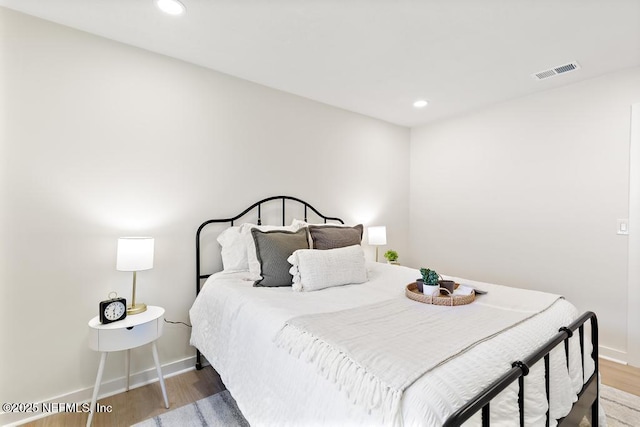 bedroom with baseboards, visible vents, wood finished floors, and recessed lighting