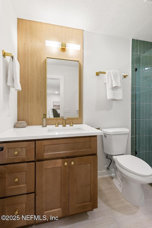 ensuite bathroom featuring connected bathroom, vanity, toilet, and a textured ceiling