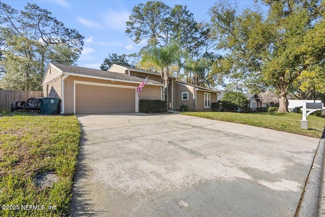 view of front of house with an attached garage, fence, concrete driveway, stucco siding, and a front yard