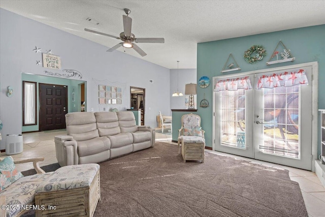 tiled living area featuring a textured ceiling, visible vents, a ceiling fan, vaulted ceiling, and french doors