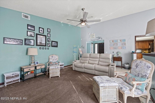 living area featuring ceiling fan, a textured ceiling, carpet flooring, visible vents, and baseboards