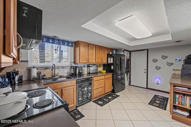 kitchen with a sink, brown cabinets, black appliances, dark countertops, and a raised ceiling