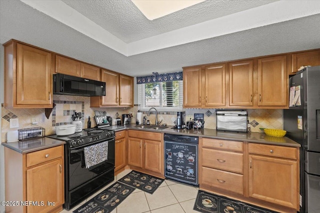 kitchen with dark countertops, a sink, black appliances, and light tile patterned floors