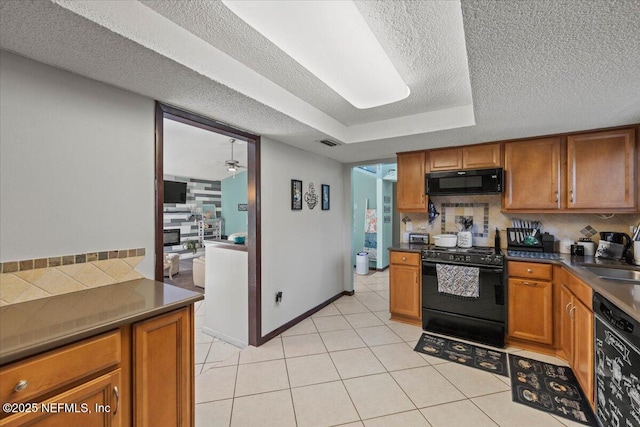 kitchen featuring visible vents, decorative backsplash, black appliances, brown cabinetry, and dark countertops