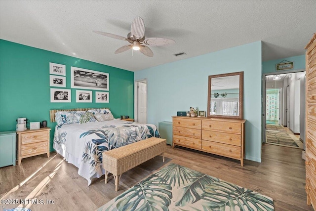 bedroom featuring a textured ceiling, visible vents, and wood finished floors