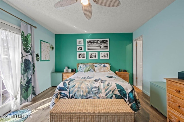 bedroom featuring a textured ceiling, wood finished floors, a ceiling fan, and baseboards