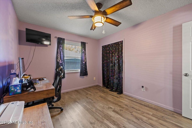 office space featuring ceiling fan, a textured ceiling, baseboards, and wood finished floors