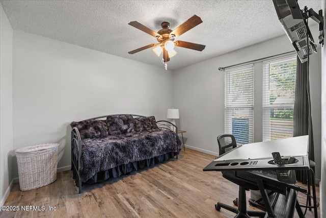 bedroom featuring a ceiling fan, a textured ceiling, baseboards, and wood finished floors