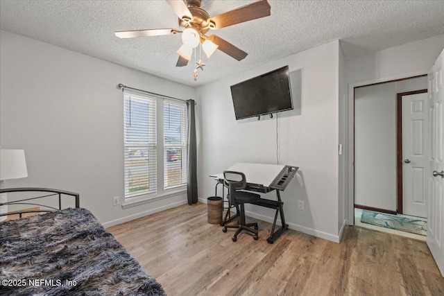 bedroom featuring baseboards, ceiling fan, a textured ceiling, and light wood finished floors