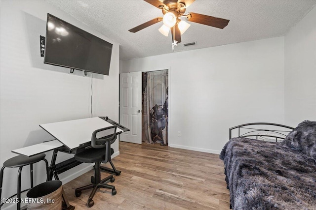 bedroom featuring visible vents, ceiling fan, a textured ceiling, light wood-type flooring, and baseboards