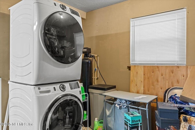 washroom with a textured ceiling, laundry area, and stacked washer / drying machine