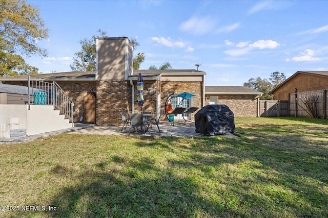 rear view of property featuring brick siding, a lawn, and fence