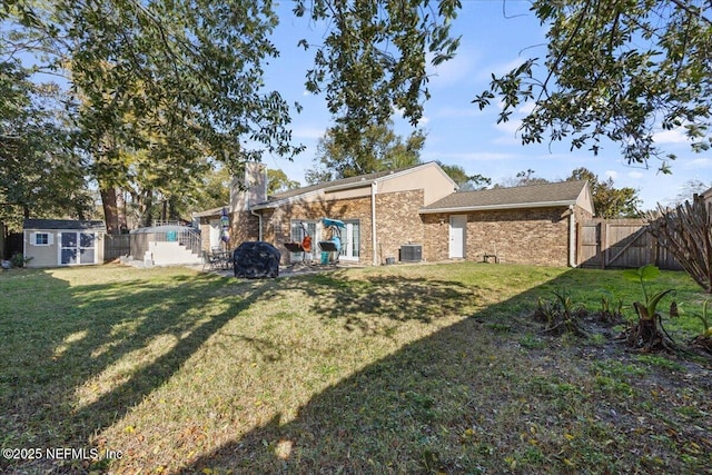 back of property with a lawn, a storage shed, a patio area, a fenced backyard, and an outdoor structure