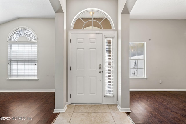 entryway featuring light tile patterned floors, lofted ceiling, and baseboards