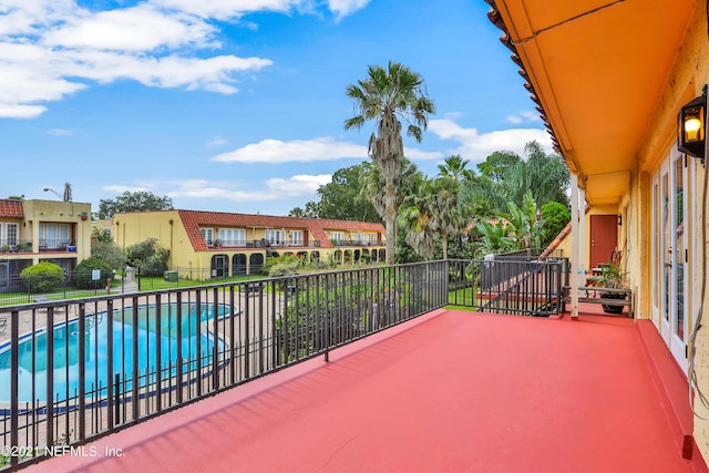 view of patio with a balcony, fence, and a fenced in pool