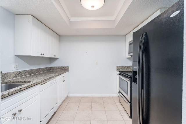 kitchen with stainless steel appliances, a tray ceiling, white cabinets, and light tile patterned flooring