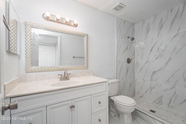 bathroom featuring a marble finish shower, visible vents, toilet, vanity, and a textured ceiling