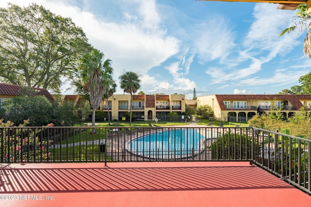 exterior space with a yard, a residential view, fence, and a community pool