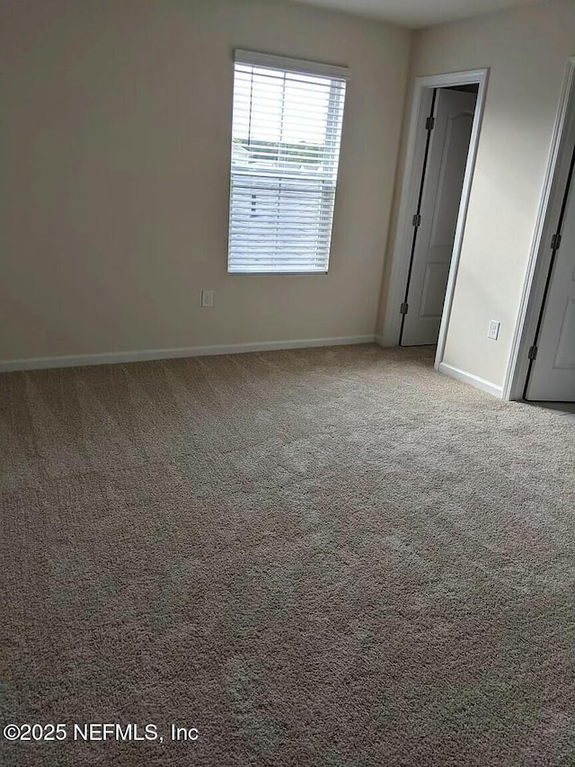 unfurnished room with carpet and baseboards