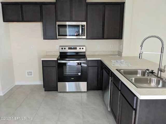 kitchen featuring stainless steel appliances, light tile patterned flooring, a sink, and light countertops