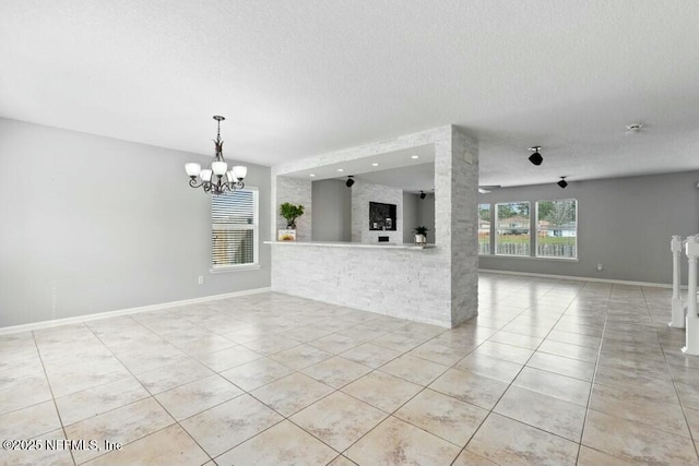 unfurnished living room featuring light tile patterned floors, baseboards, a textured ceiling, and an inviting chandelier