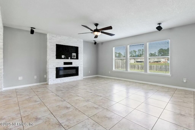 unfurnished living room featuring baseboards, a ceiling fan, a textured ceiling, a fireplace, and light tile patterned flooring