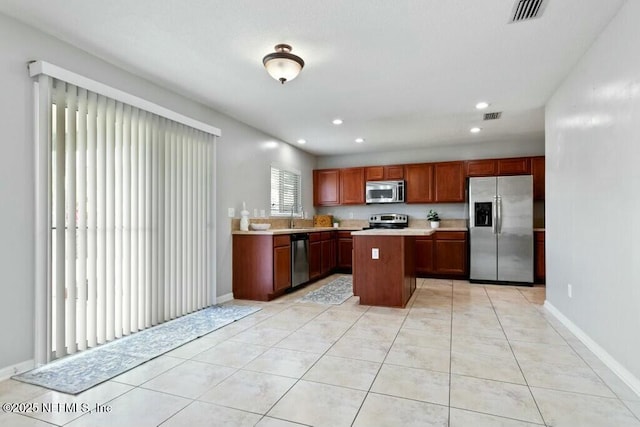 kitchen with light tile patterned floors, visible vents, a center island, stainless steel appliances, and light countertops