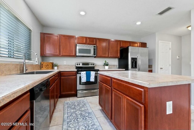 kitchen featuring visible vents, a kitchen island, appliances with stainless steel finishes, light countertops, and a sink