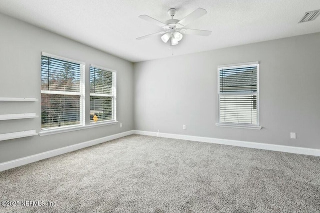 spare room with carpet floors, visible vents, a ceiling fan, a textured ceiling, and baseboards