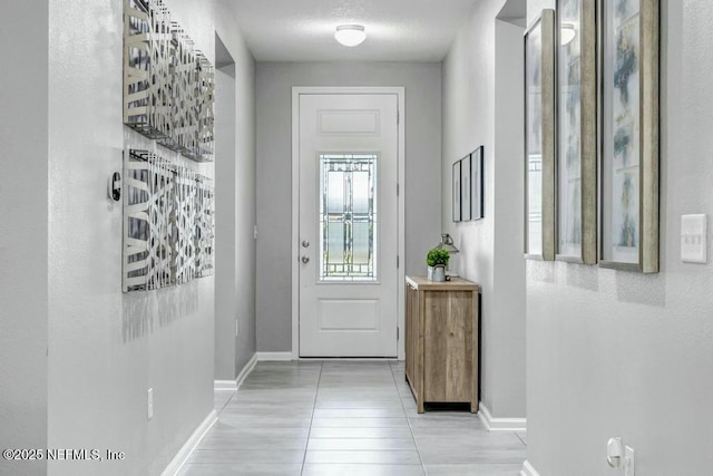 doorway to outside featuring light tile patterned floors and baseboards