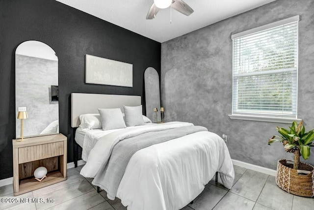 bedroom featuring an accent wall, arched walkways, baseboards, and a ceiling fan