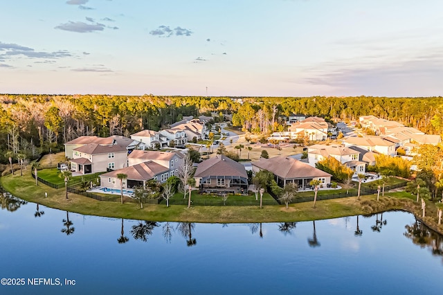 drone / aerial view with a water view, a residential view, and a wooded view