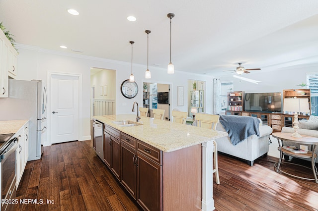 kitchen with appliances with stainless steel finishes, a sink, a kitchen breakfast bar, and dark wood-style floors