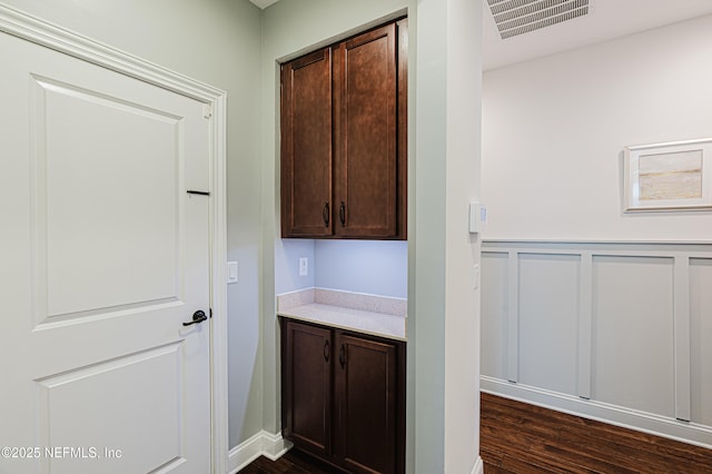 bar with a wainscoted wall, dark wood-type flooring, and visible vents