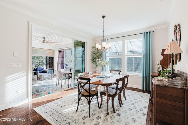 dining space featuring a notable chandelier, baseboards, crown molding, and wood finished floors