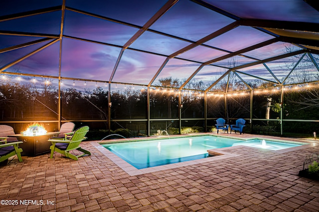 pool at dusk featuring a lanai, a patio area, an outdoor fire pit, and an outdoor pool