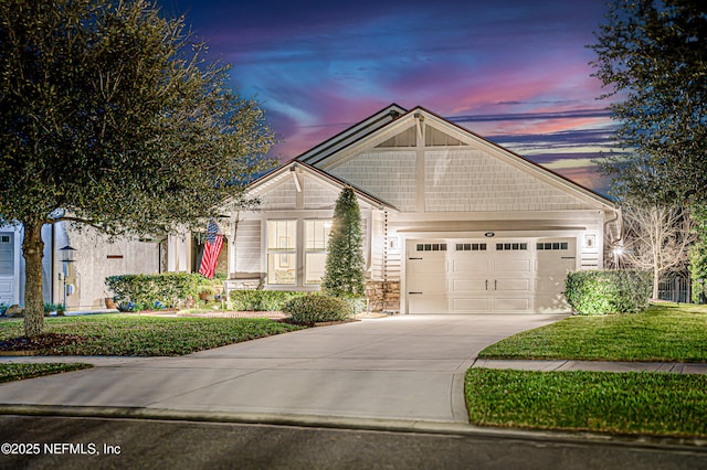 craftsman house with a garage, concrete driveway, a yard, and stone siding