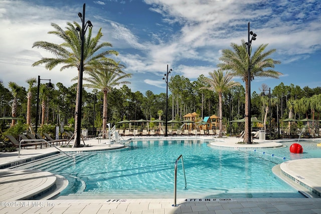 community pool featuring a patio, playground community, and fence