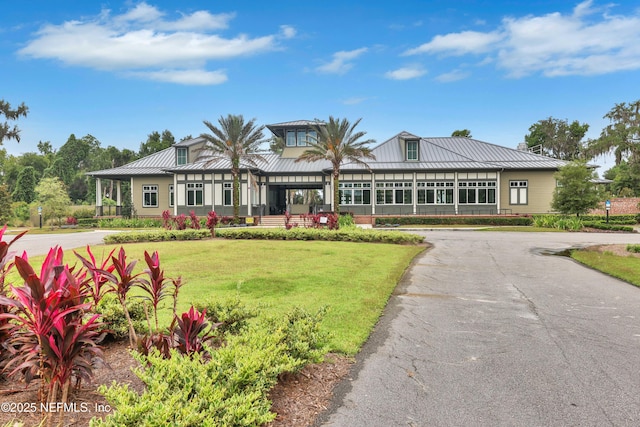 view of front facade with a standing seam roof, metal roof, and a front lawn