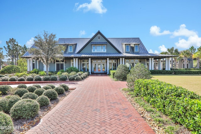 view of front of property featuring metal roof, french doors, decorative driveway, a front lawn, and a standing seam roof