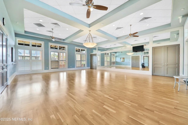 exercise room with a ceiling fan, light wood-type flooring, and visible vents