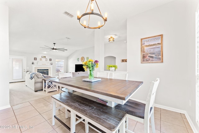 dining space featuring light tile patterned floors, visible vents, vaulted ceiling, a fireplace, and ceiling fan with notable chandelier