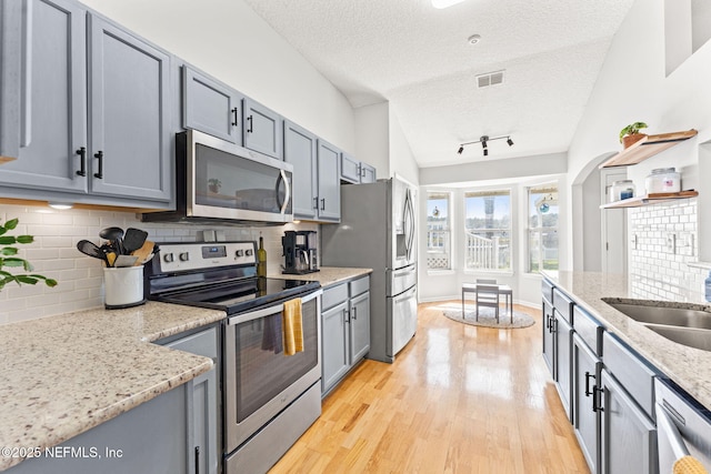 kitchen with visible vents, stainless steel appliances, a textured ceiling, light wood-type flooring, and backsplash