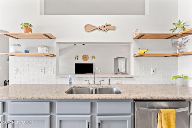 kitchen featuring light stone countertops, a sink, stainless steel dishwasher, and open shelves