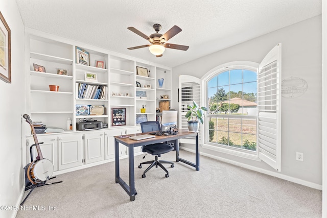 office with a ceiling fan, light colored carpet, a textured ceiling, and baseboards