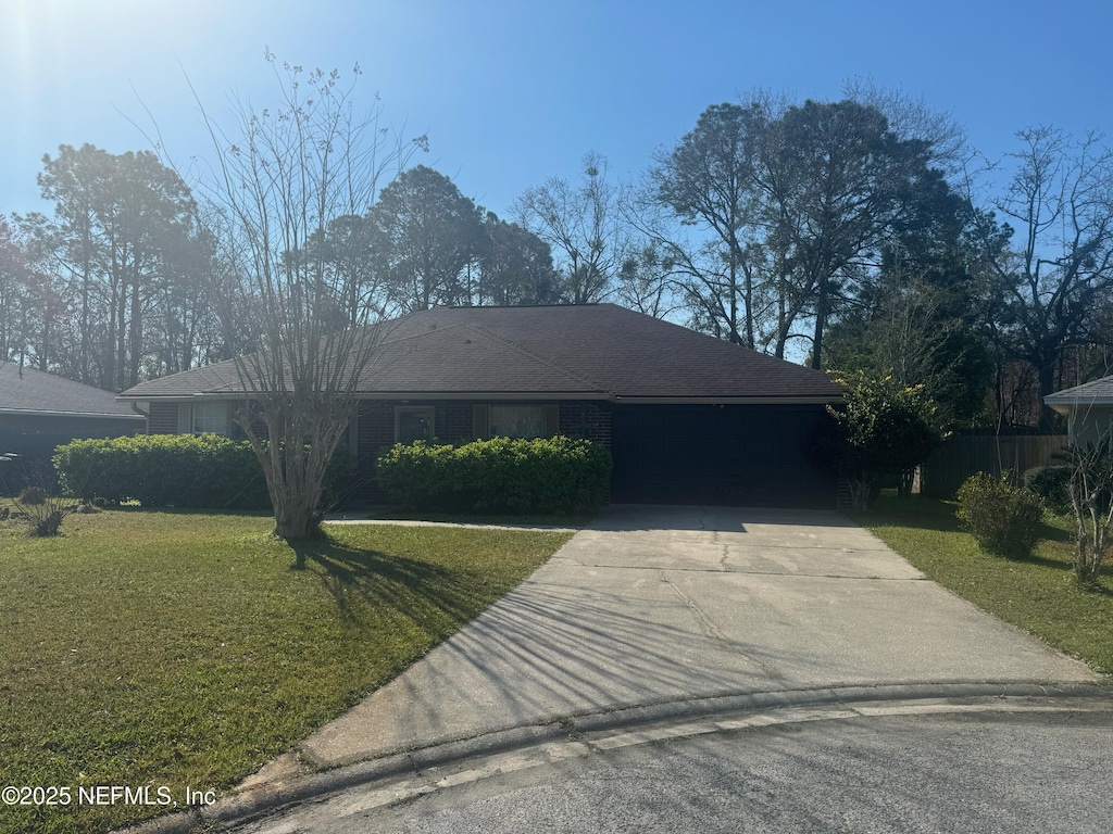 single story home with a front lawn, an attached garage, and driveway