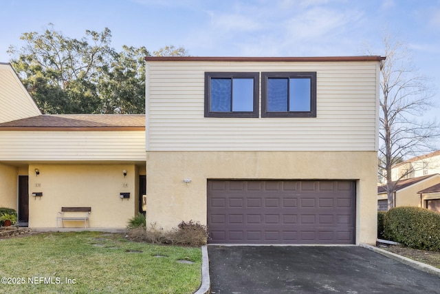 view of front of property with an attached garage, a front lawn, aphalt driveway, and stucco siding